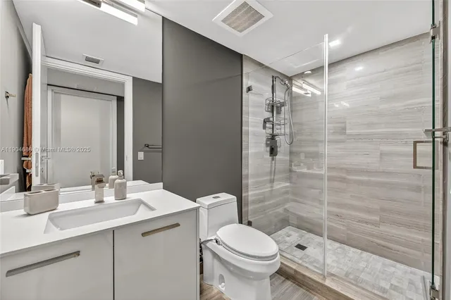 a bathroom with a shower sink vanity mirror and toilet
