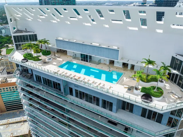 a large white building with a swimming pool and outdoor seating