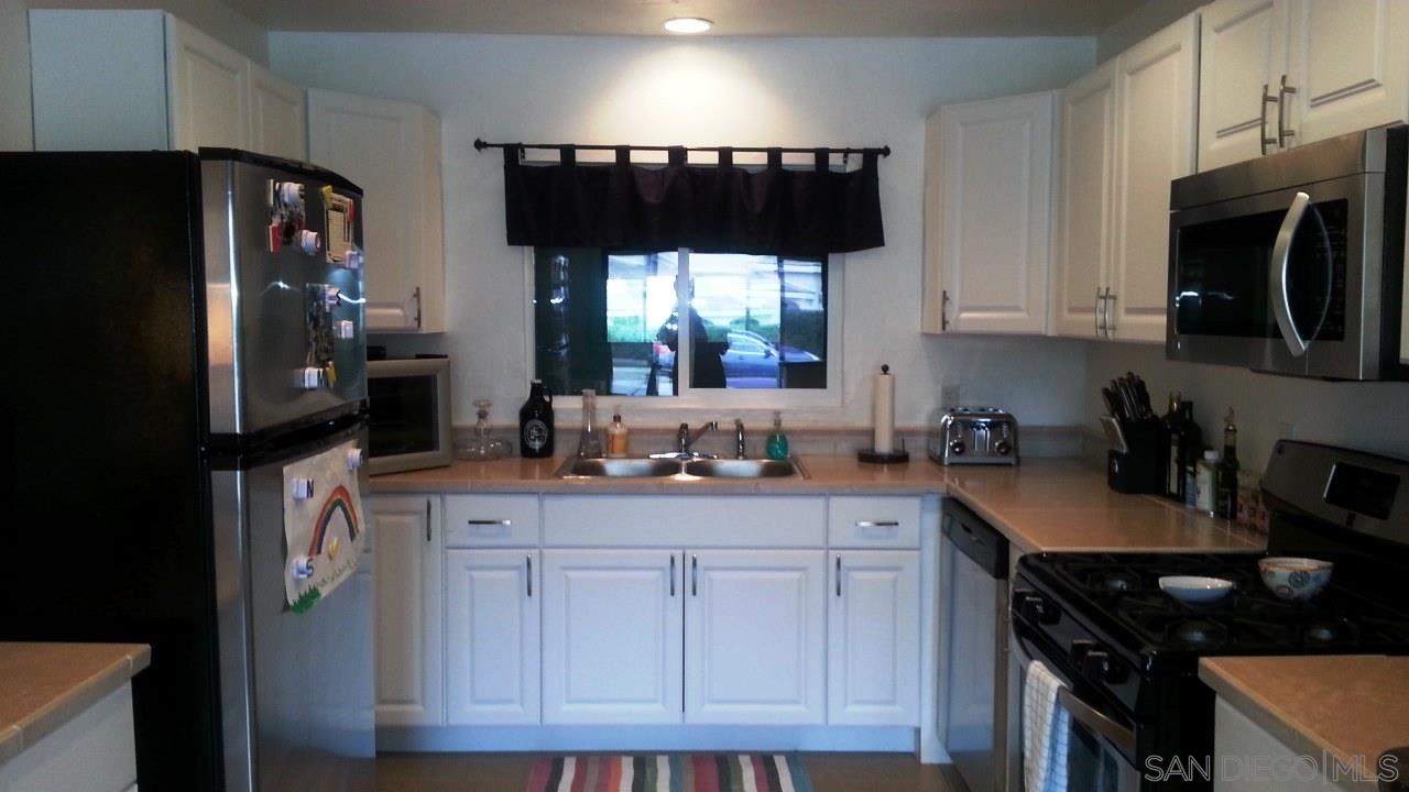 a kitchen with granite countertop a refrigerator stove top oven a sink and dishwasher