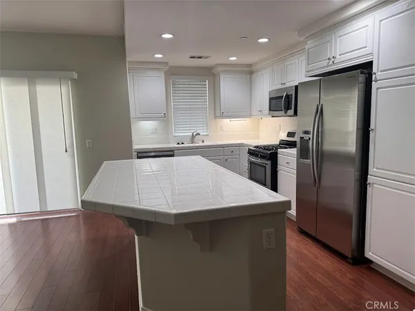 a kitchen with stainless steel appliances a refrigerator a sink a stove a microwave and wooden floor
