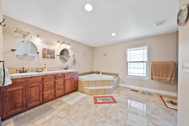 a spacious bathroom with a tub sink and mirror