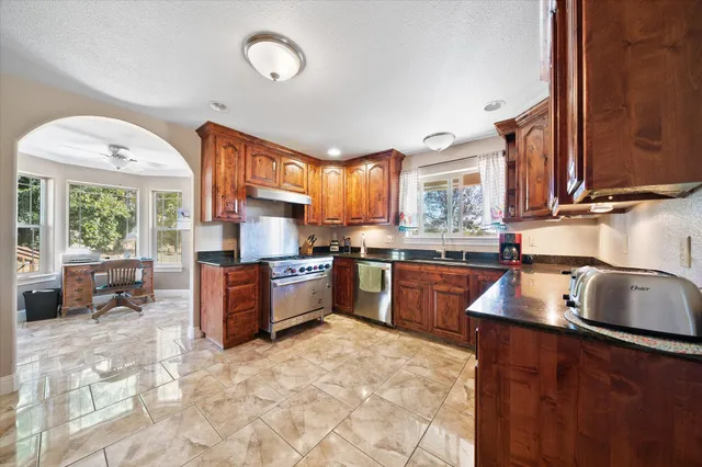 a kitchen with stainless steel appliances granite countertop a stove sink and cabinets