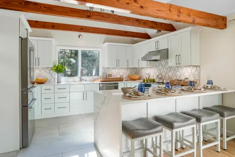 a kitchen with white cabinets and wooden floor