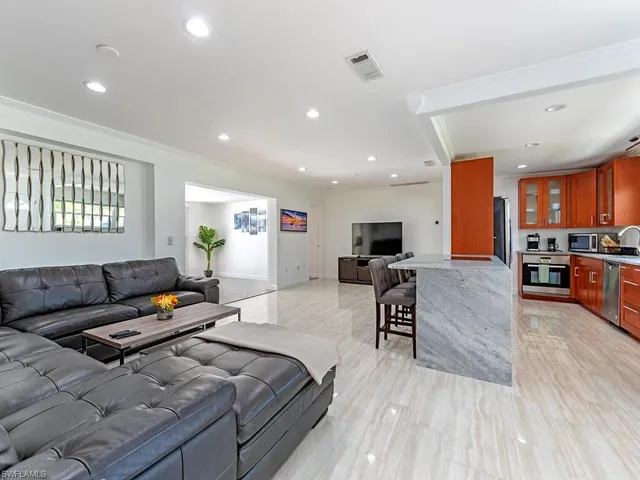 a living room with furniture and a flat screen tv with kitchen view