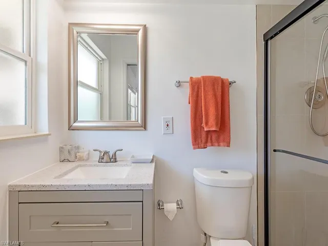 a bathroom with a granite countertop sink a toilet and mirror