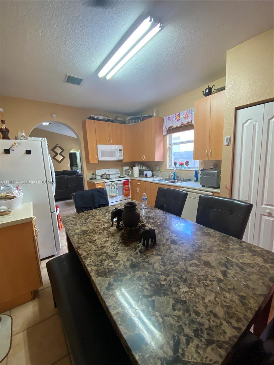 2101 Northeast 37th Road Homestead, FL 33033 - Photo 7 of 11 a large kitchen with a table chairs in it and wooden floors