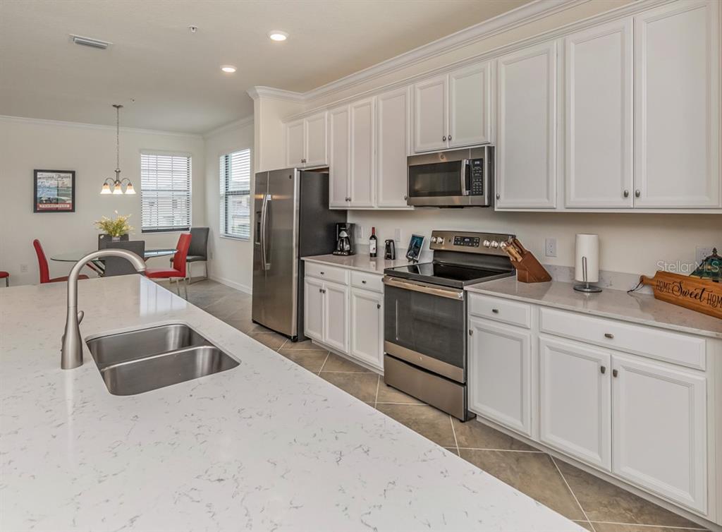 12550 Ghiberti Circle, Unit 201 Venice, FL 34293 - Photo 5 of 44 a kitchen with granite countertop a sink stainless steel appliances and white cabinets
