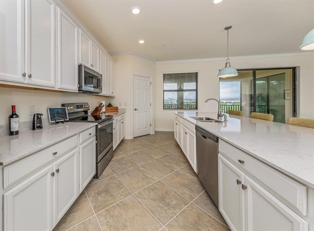 12550 Ghiberti Circle, Unit 201 Venice, FL 34293 - Photo 6 of 44 a large white kitchen with stainless steel appliances granite countertop lots of counter top space and a window