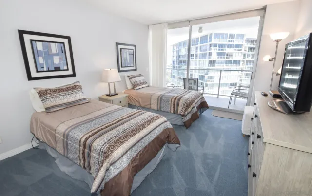 a bedroom with two beds and a flat tv screen on the dresser