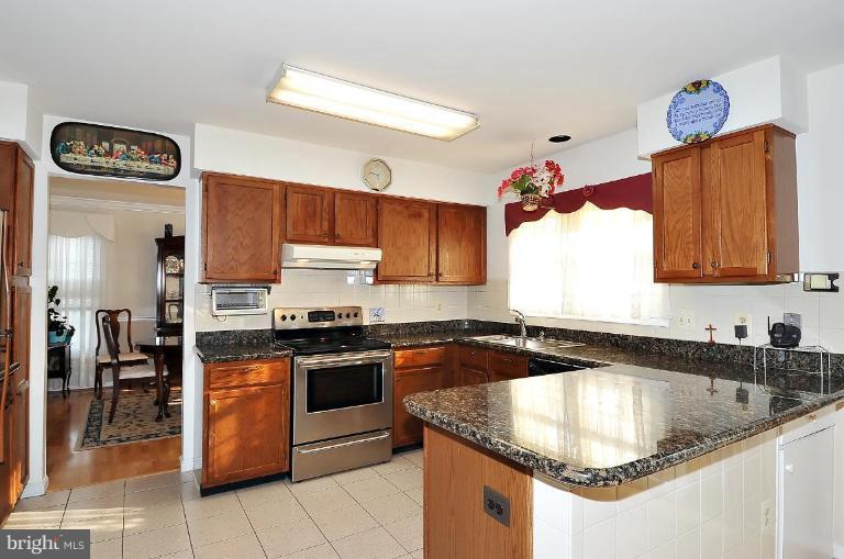 4107 Ulster Road Beltsville, MD 20705 - Photo 8 of 21 a kitchen with granite countertop a sink a stove and lots of wooden cabinets