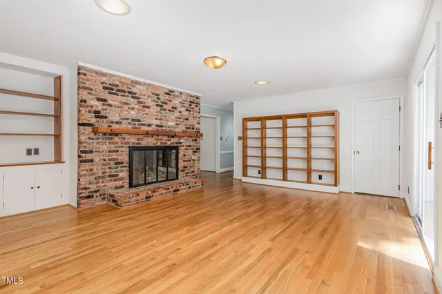 a view of empty room with wooden floor and fireplace