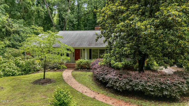 a view of a house with a yard plants and large tree