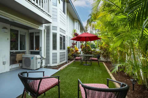 a view of a backyard with table and chairs under an umbrella with a fire pit