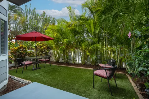 a view of a yard with a table and chair under an umbrella