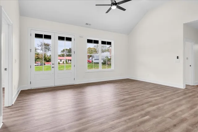 a view of an empty room with window and wooden floor