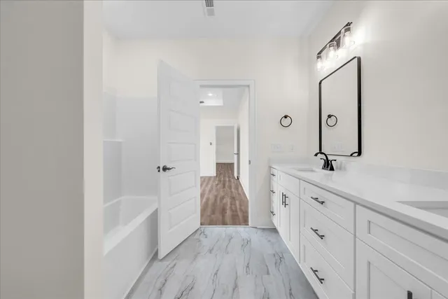 a spacious bathroom with a bathtub sink and mirror