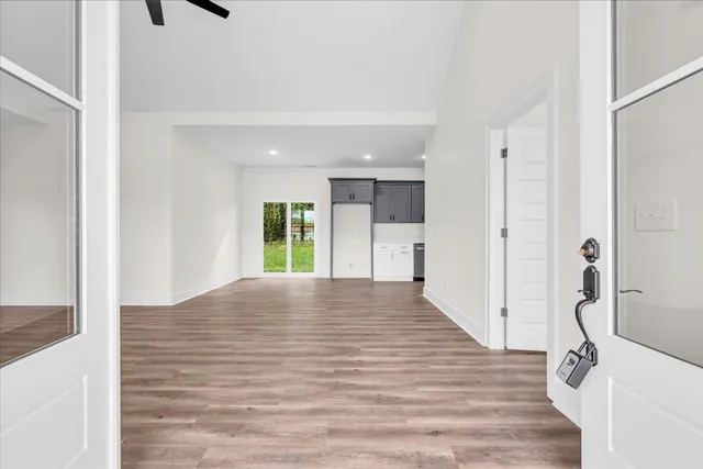 a view of a hallway with wooden floor and a bathroom