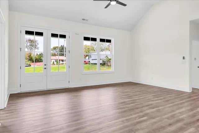 an empty room with wooden floor and windows