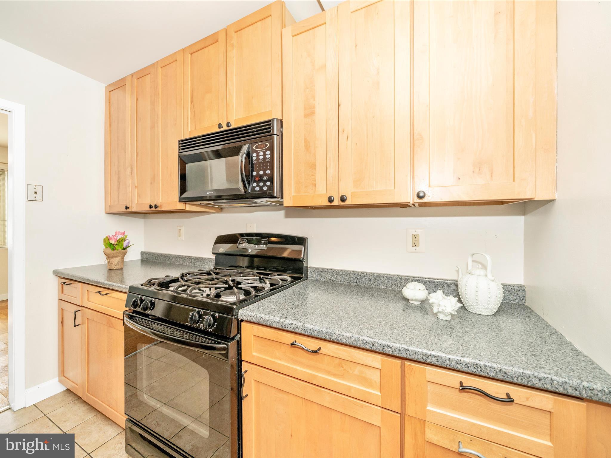 3900 Tunlaw Road Northwest, Unit 613 Washington, DC 20007 - Photo 20 of 31 a kitchen with granite countertop a stove a sink and a white cabinets