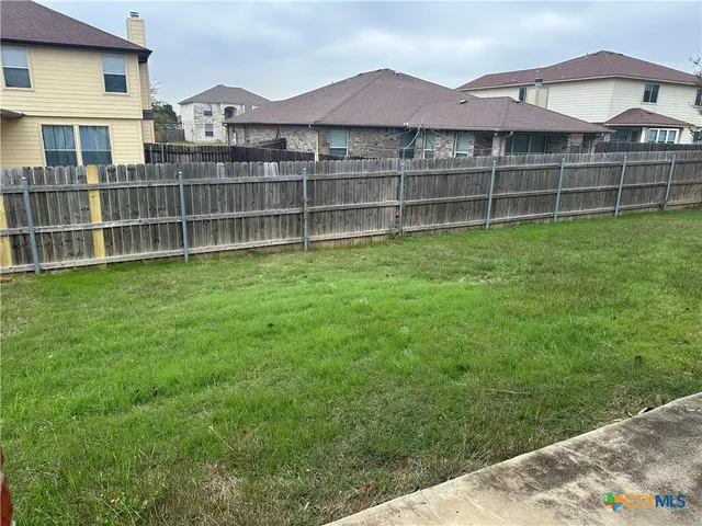 a view of a house with a yard and wooden fence