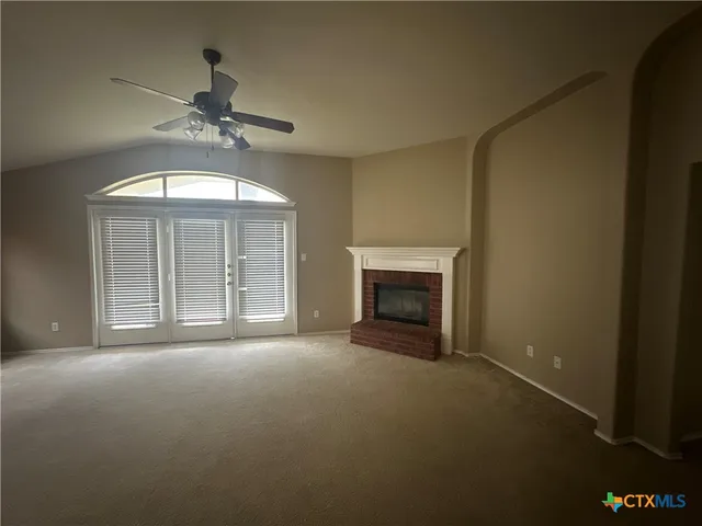 a view of an empty room with a fireplace and a window