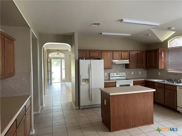a kitchen with stainless steel appliances granite countertop a refrigerator a stove top oven and a sink