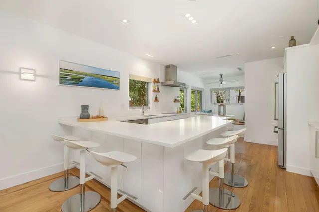 a kitchen with stainless steel appliances granite countertop a sink a stove a refrigerator and a dining table with wooden floor