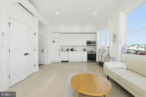 a view of kitchen with furniture a refrigerator and white cabinets