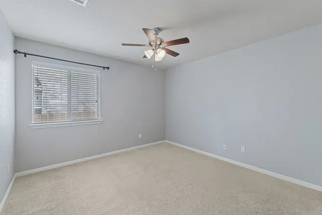 an empty room with a window and a fan