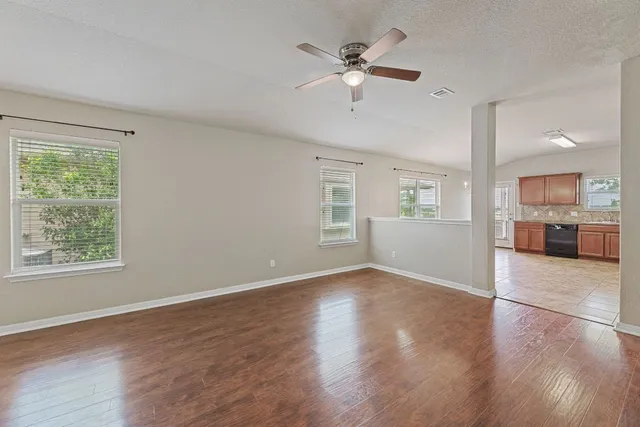 a view of an empty room with a window and wooden floor