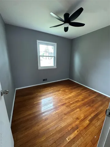 an empty room with ceiling fan and window