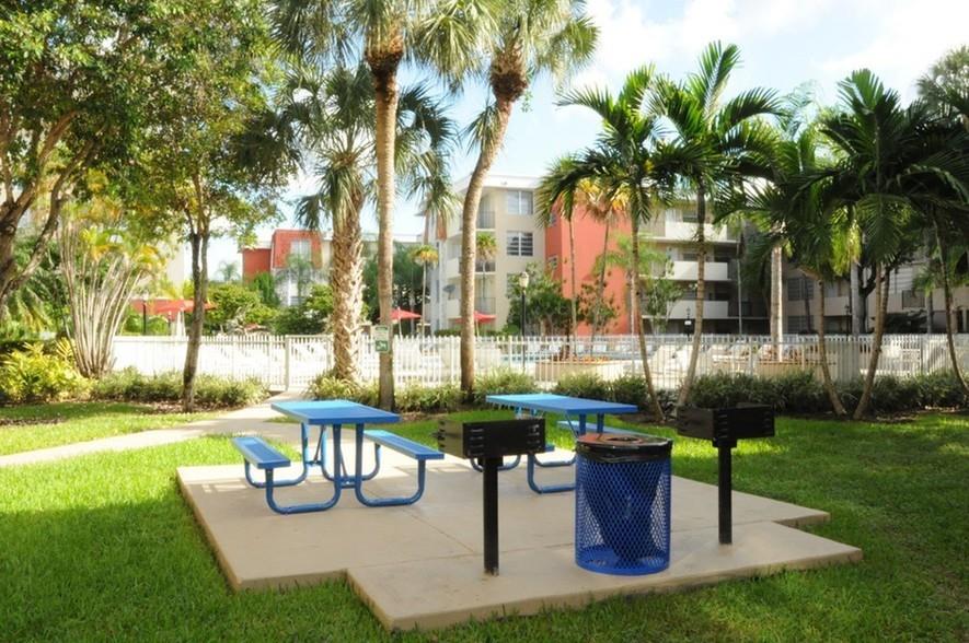 9357 Southwest 77th Avenue, Unit 851032 Miami, FL 33156 - Photo 11 of 17 a view of a patio with table and chairs potted plants and palm tree