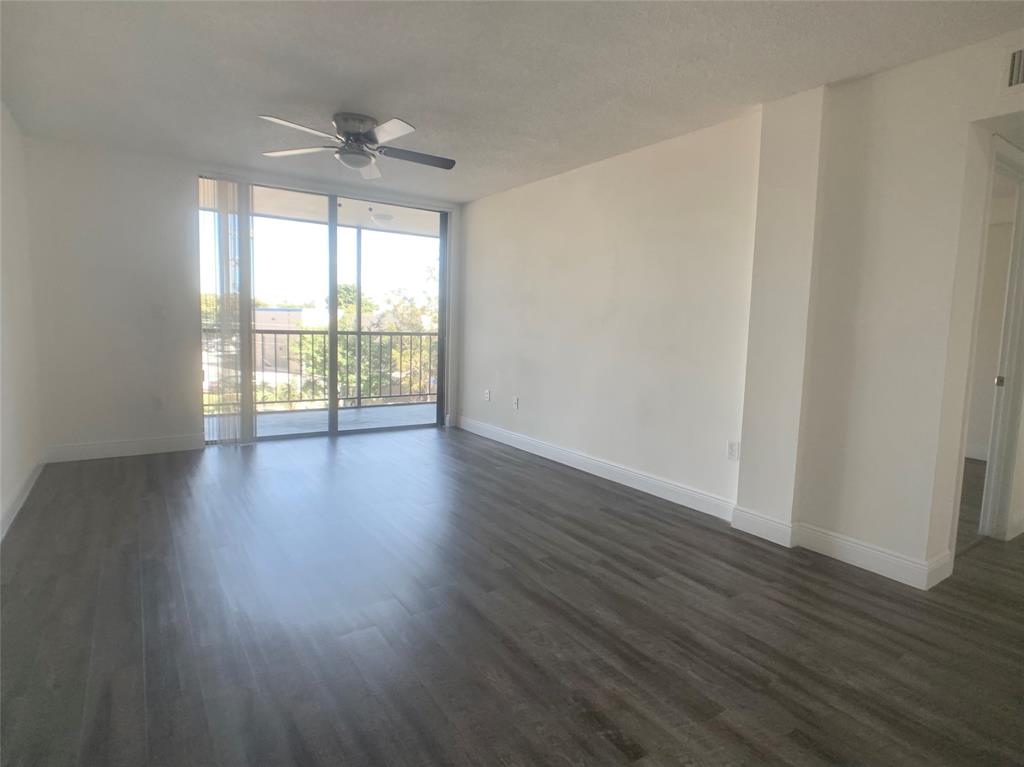 9357 Southwest 77th Avenue, Unit 851032 Miami, FL 33156 - Photo 2 of 17 a view of an empty room with wooden floor and a window