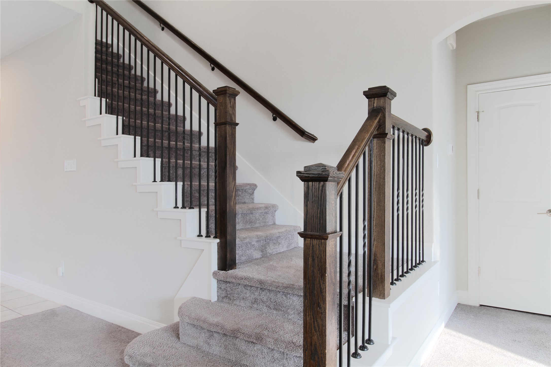 109 Yellow Thistle Cove Georgetown, TX 78626 - Photo 22 of 36 Carpeted staircase featuring dark wood newel posts and handrail with black iron balusters