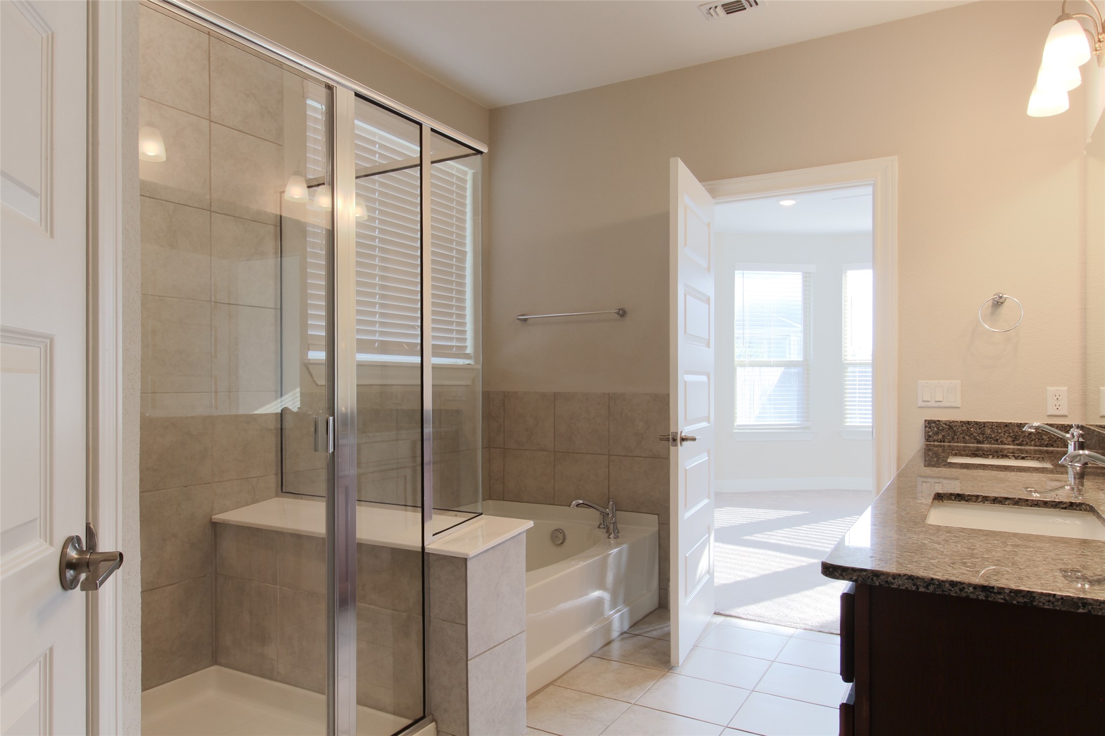 109 Yellow Thistle Cove Georgetown, TX 78626 - Photo 26 of 36 Tiled bathroom featuring a glass-enclosed shower, a separate soaking tub, and a vanity with a stone countertop and double sinks