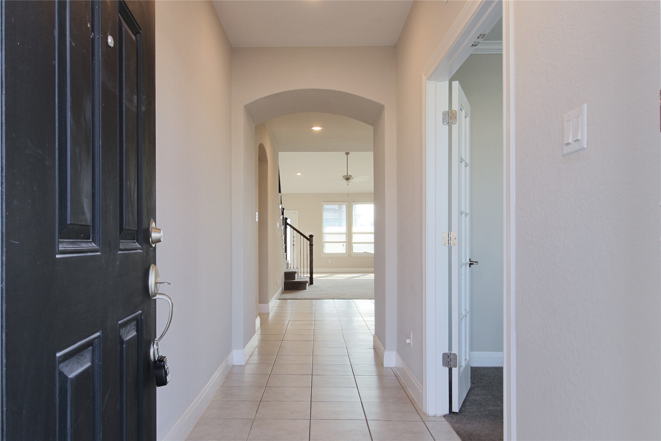 109 Yellow Thistle Cove Georgetown, TX 78626 - Photo 3 of 36 Entryway featuring a black paneled front door, ceramic tile flooring, an arched doorway, and a white interior door with glass panels