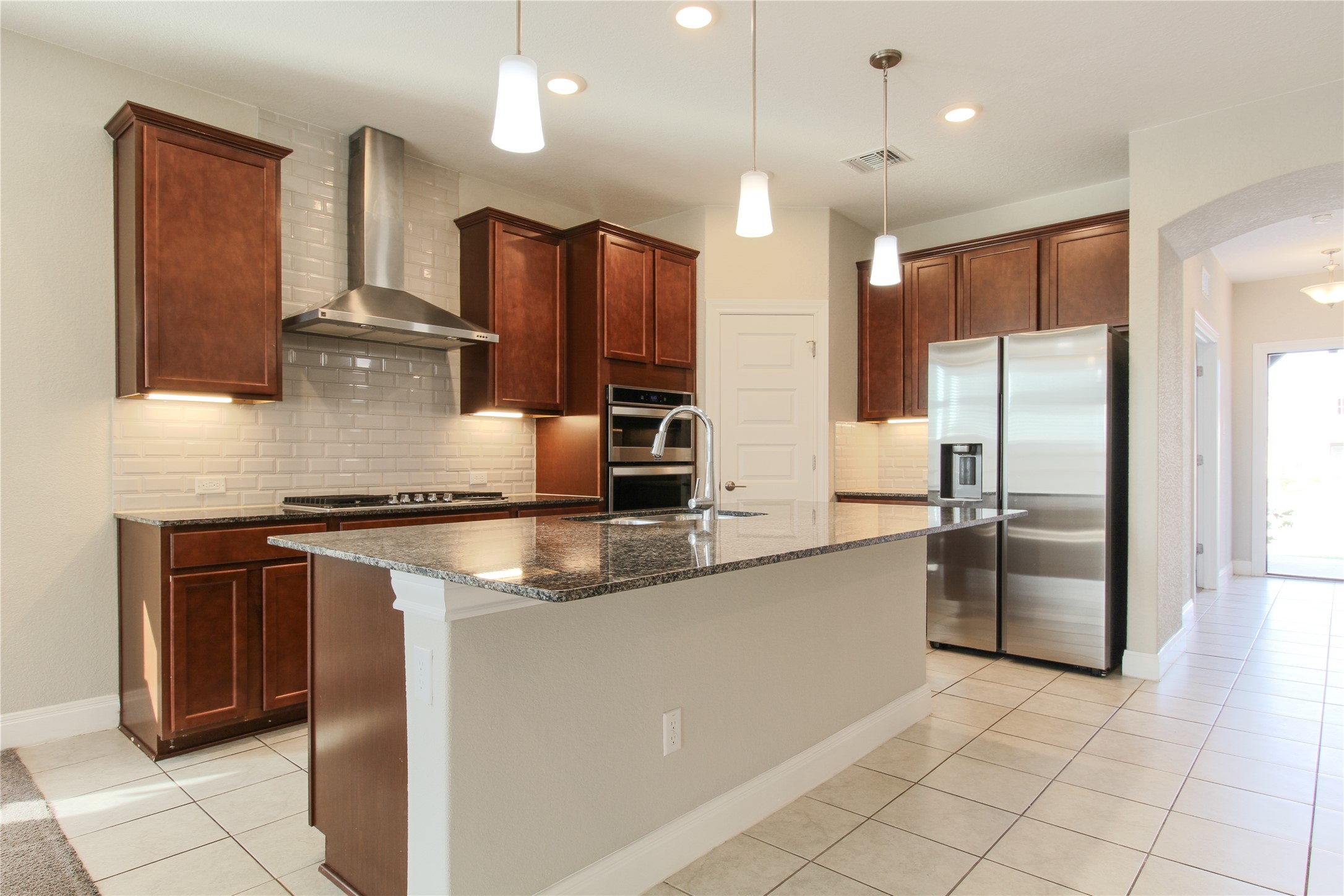 109 Yellow Thistle Cove Georgetown, TX 78626 - Photo 6 of 36 Kitchen featuring wood-finish cabinetry, stainless steel appliances, a center island with a speckled countertop, and white subway tile backsplash