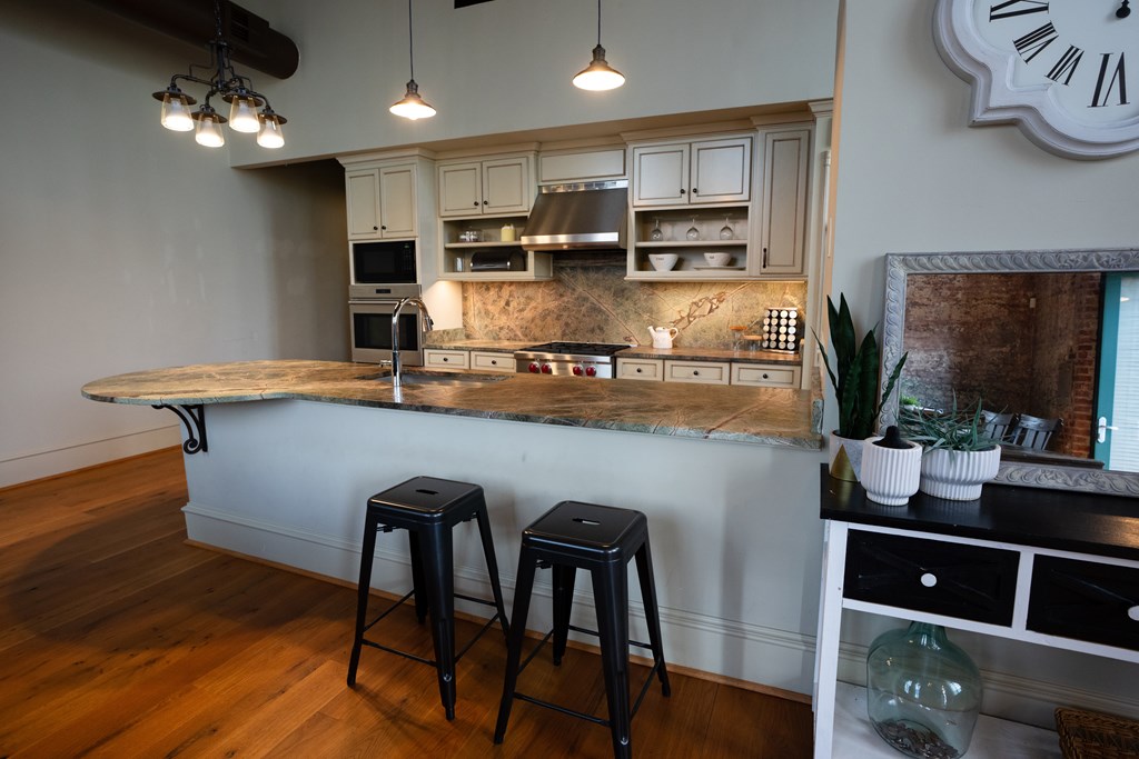 1201 Front Avenue, Unit 203 Columbus, GA 31901 - Photo 3 of 54 a kitchen with kitchen island stainless steel appliances a dining table chairs sink and wooden floor