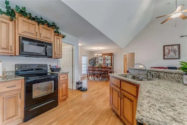 a kitchen with stainless steel appliances granite countertop a stove a sink dishwasher and a refrigerator with wooden floor