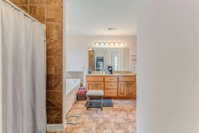a bathroom with a granite countertop tub sink and mirror