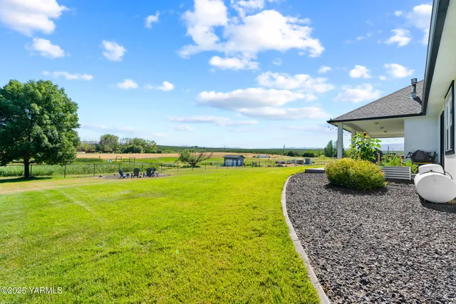 a view of a big house with a big yard and large trees