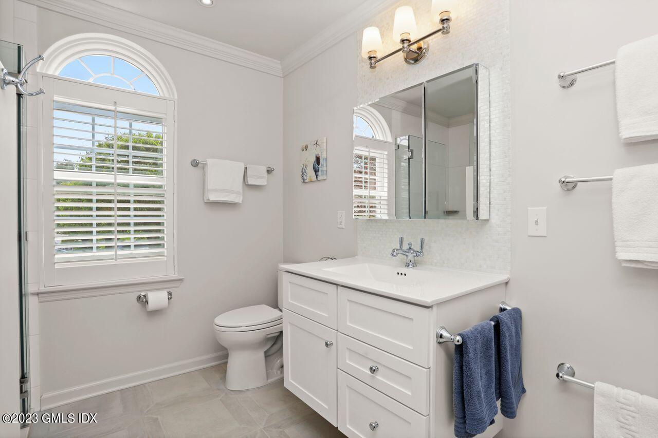 1 Shore Road, Unit 3 Stamford, CT 06902 - Photo 27 of 37 a bathroom with a toilet a sink a mirror a window and vanity