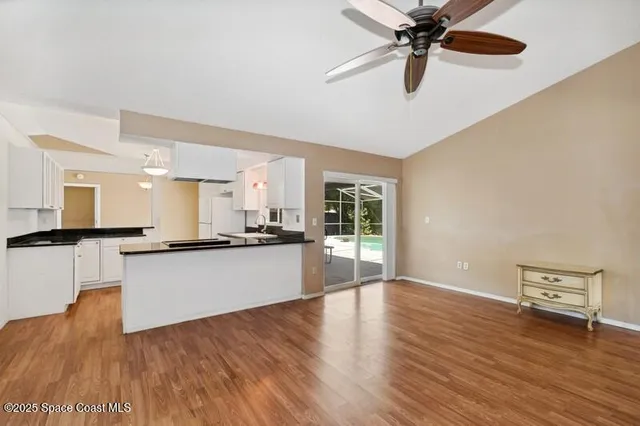 a large kitchen with a wooden floor and a ceiling fan