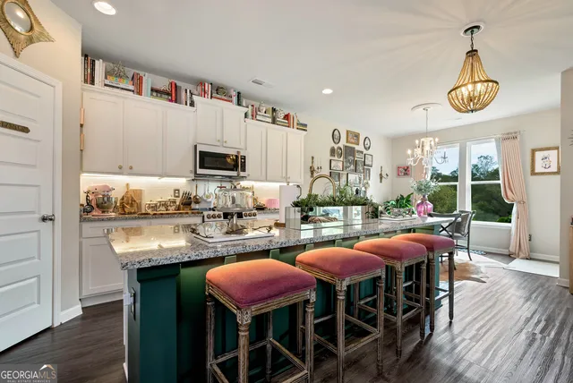 a kitchen with stainless steel appliances granite countertop a stove a kitchen island a dining table and chairs with wooden floor