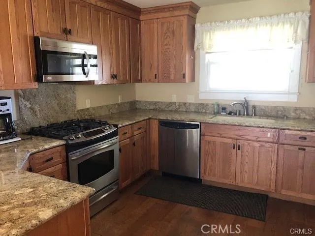 a kitchen with granite countertop a sink stove and microwave
