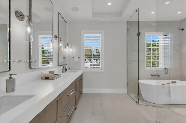 a bathroom with a double vanity sink large mirror and a bathtub
