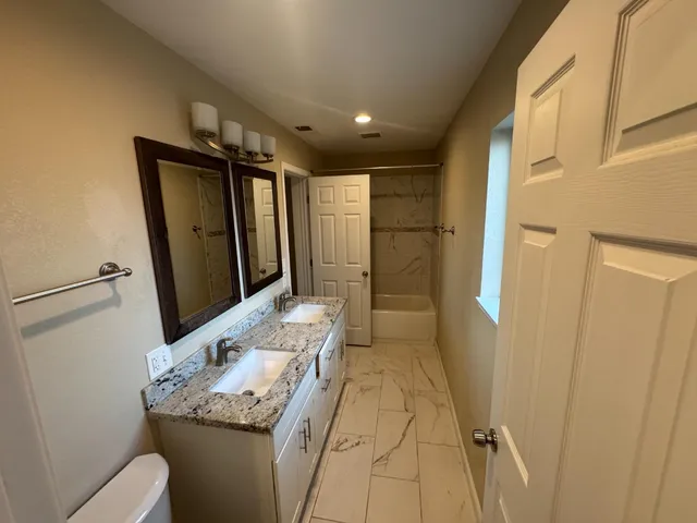 a bathroom with a granite countertop sink a mirror and a shower