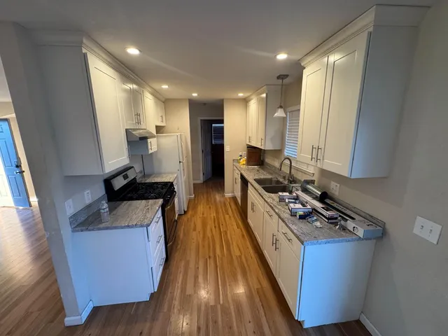 a kitchen with sink refrigerator and wooden floor
