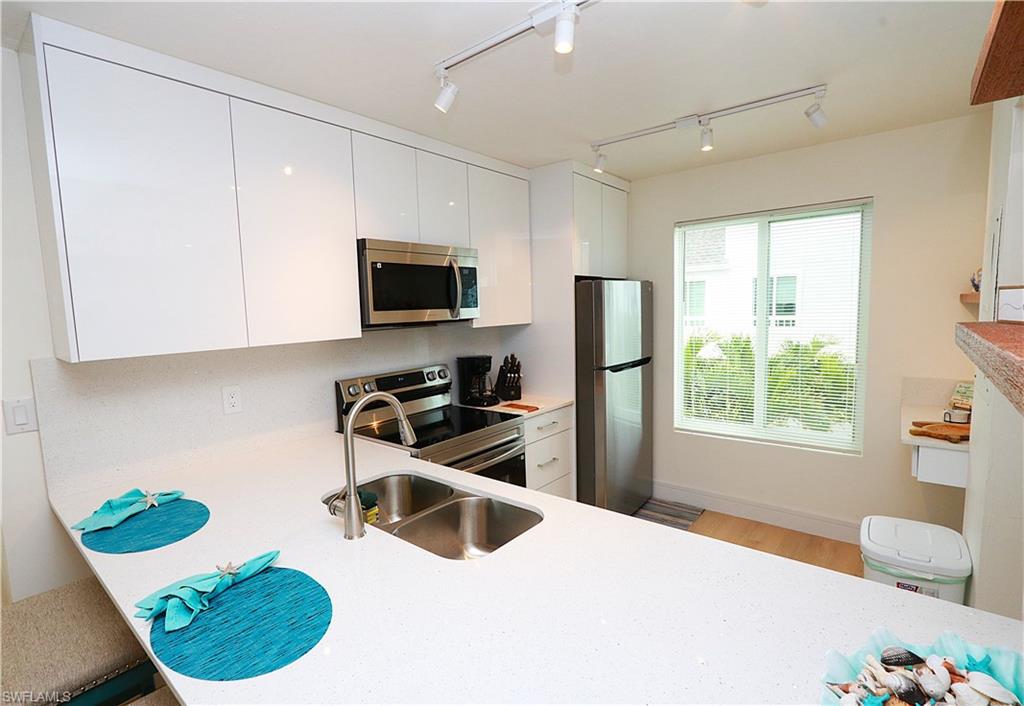 2235 San Marco Road, Unit 5204 Marco Island, FL 34145 - Photo 12 of 42 Kitchen with white cabinets, appliances with stainless steel finishes, modern cabinets, and rail lighting