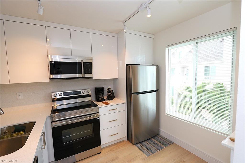 2235 San Marco Road, Unit 5204 Marco Island, FL 34145 - Photo 13 of 42 Kitchen featuring appliances with stainless steel finishes, rail lighting, modern cabinets, light wood-style flooring, and white cabinetry